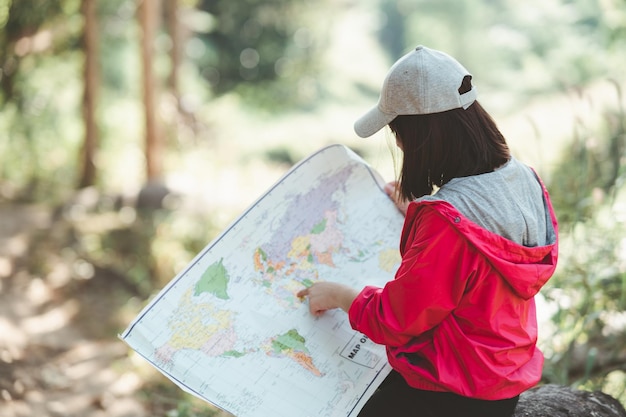 Mão de mulher apontando o dedo segurando e olhando para mapear a mochila de direção no caminho da floresta tropical enquanto caminhava na selva Viajando férias e viagem de férias conceito de viagem de sobrevivência