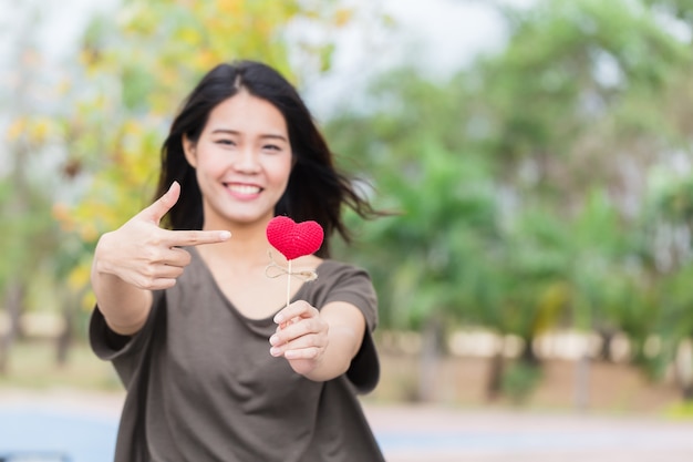 Mão de mulher asiática segurar lindo coração vermelho doce símbolo amoroso