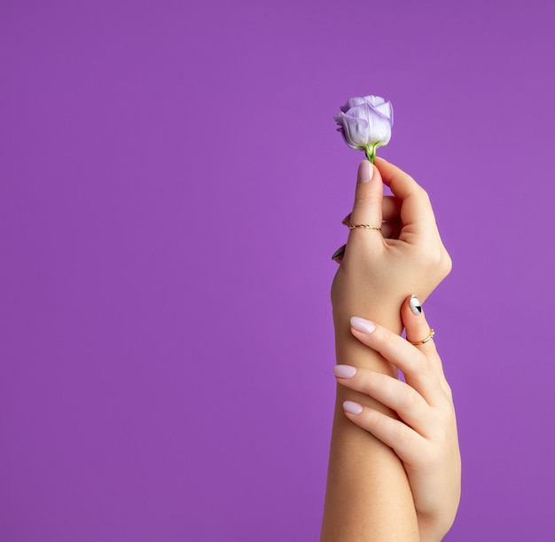 Mão de mulher bonita com design primavera verão em fundo violeta Conceito de salão de beleza manicure pedicure