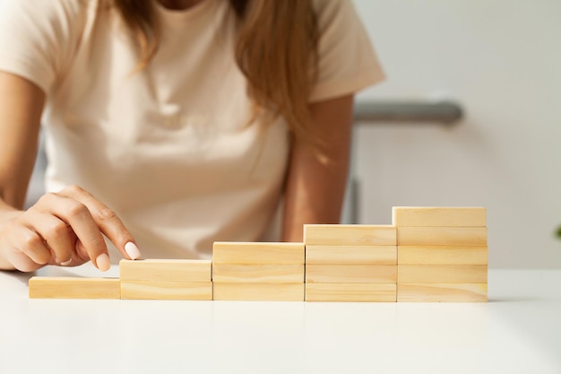 Mão de mulher colocando e empilhando cubos de madeira em branco na mesa com espaço de cópia para texto de entrada