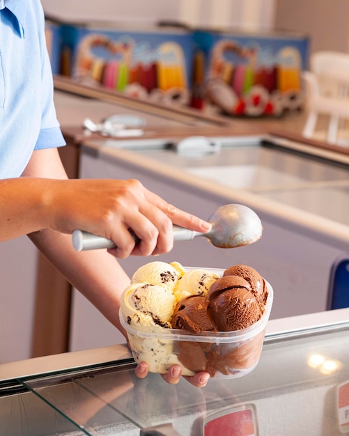 Mão de mulher colocando sorvete cremoso no pote para levar para casa espaço para texto