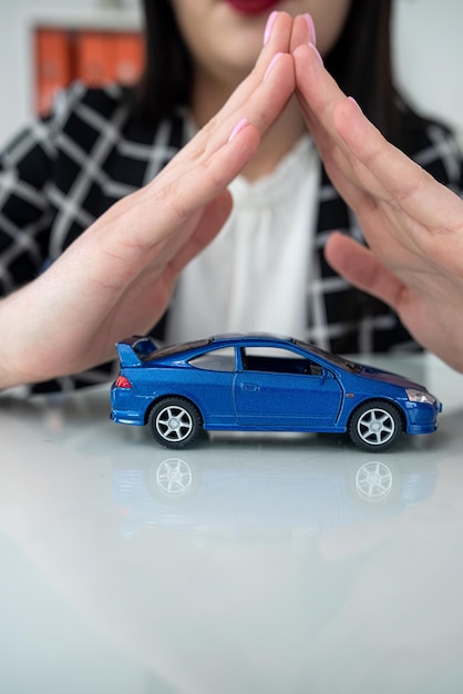 Foto mão de mulher com carro de brinquedo como conceito de seguro de proteção apoio