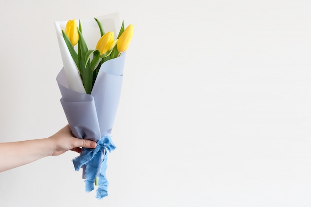 Mão de mulher com manicure segurando flores da primavera.