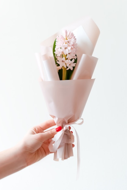 Mão de mulher com manicure segurando flores da primavera.