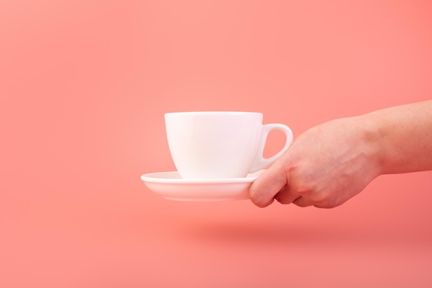 Mão de mulher com tema de café da manhã e café segurando uma xícara de café de cerâmica vazia branca anunciando café