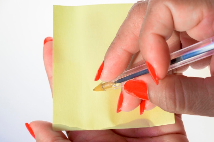 Foto mão de mulher com unhas pintadas segurando um poste em fundo branco puro
