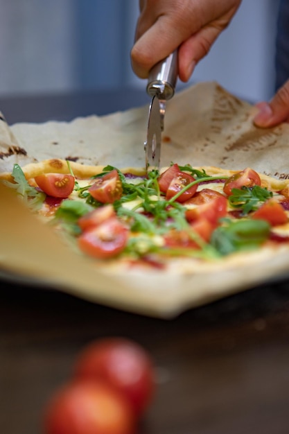 Mão de mulher cortando pizza para pedaços