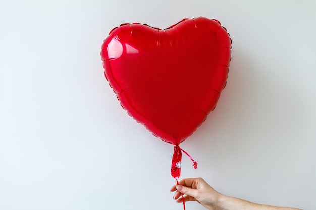 Mão de mulher de conceito de São Valentim segurando um balão de coração vermelho isolado no fundo branco pessoa p ...