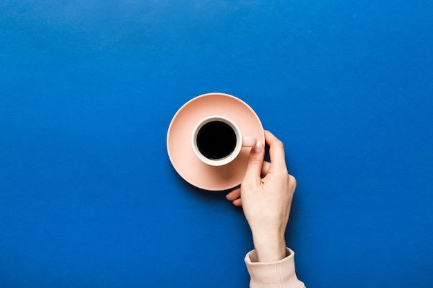 Mão de mulher de estilo minimalista segurando uma xícara de café em Fundo colorido Vista superior plana xícara de café Lugar vazio para espaço de cópia de texto Vício em café Vista superior plana leigos
