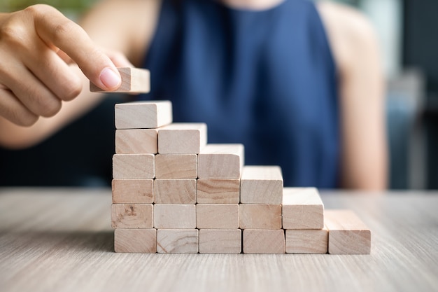 Mão de mulher de negócios, colocando ou puxando o bloco de madeira