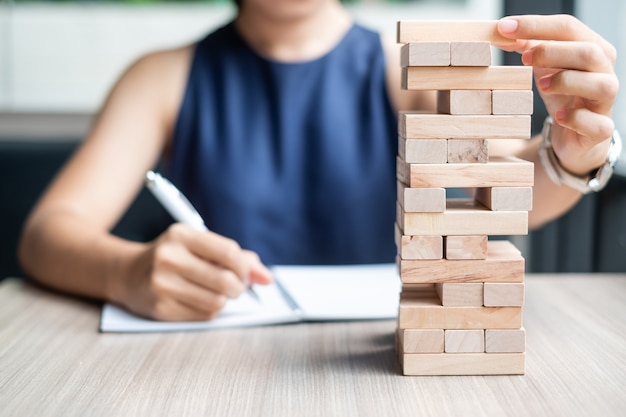 Mão de mulher de negócios, colocando ou puxando o bloco de madeira