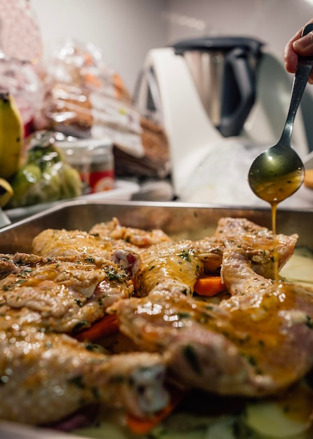 Mão de mulher derramando azeite marinado em frango preparando-o para assar