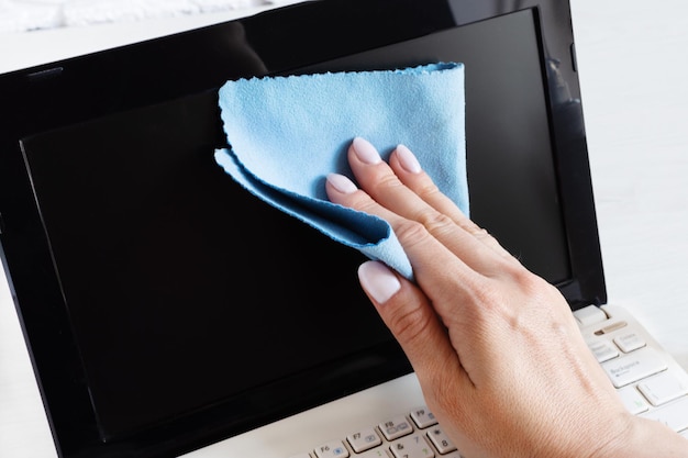 Mão de mulher desinfetando a tela do computador com pano antibacteriano