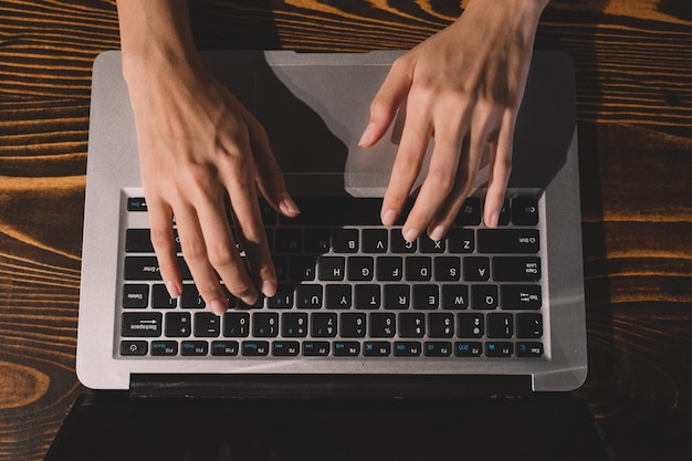 Foto mão de mulher digitando no teclado no local de trabalho empresária trabalhando sobre labtop em uma mesa de madeira fazendo trabalho em casa closeup imagem de mão de trabalho de comunicação empresarial