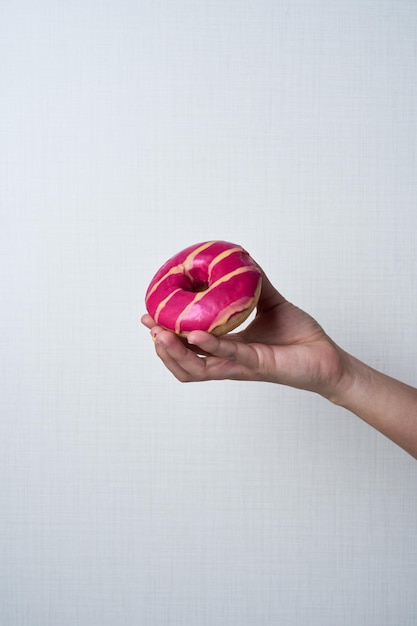 Mão de mulher irreconhecível mostrando um conceito de pastelaria de rosquinhas multicoloridas