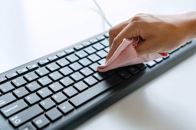 Mão de mulher, limpeza de teclado com pano de microfibra