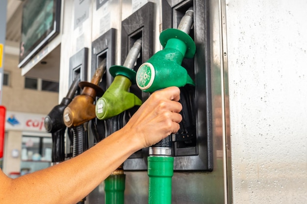 Foto mão de mulher na bomba automática de gasolina ou diesel no posto de gasolina