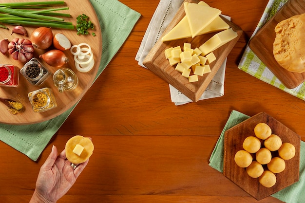 Mão de mulher preparando croquete recheado com queijo bolinha de queijo em uma mesa de madeira vista superior