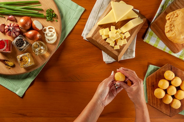 Mão de mulher preparando croquete recheado com queijo bolinha de queijo em uma mesa de madeira Vista superior