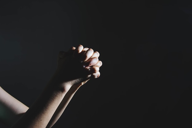 mão de mulher reza no escuro (rezando no conceito de quarto secreto)