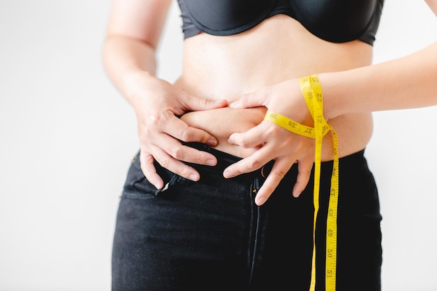 Mão de mulher segurando a gordura da barriga excessiva barriga gorda com excesso de peso da mulher gorda mulher gorda estilo de vida da dieta da mulher para reduzir o conceito de gordura e saúde da barriga