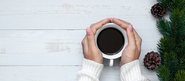 Mão de mulher segurando a xícara de café preto com decoração de Natal, feliz ano novo e feriados de Natal