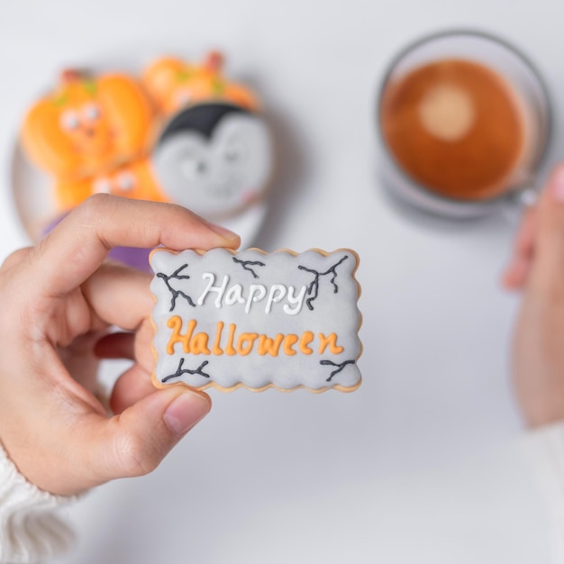 Mão de mulher segurando engraçado biscoito de Halloween durante o café feliz dia de Halloween Truque ou Ameaça Olá outubro outono outono Festa tradicional e conceito de férias