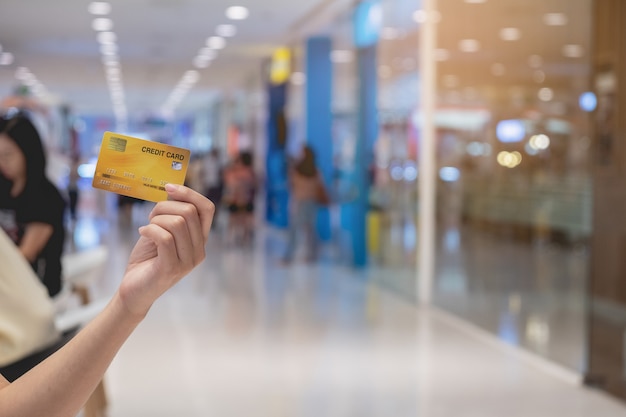 Mão de mulher segurando o cartão de crédito turva