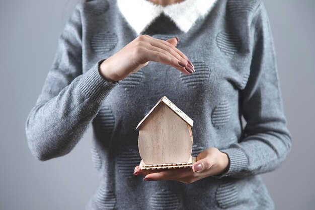 Mão de mulher segurando o modelo de casa