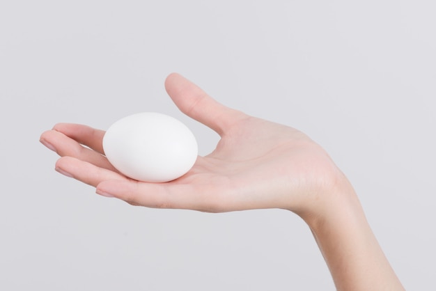 Mão de mulher segurando ovo branco isolado no branco