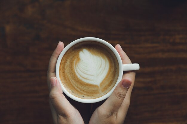 Mão de mulher segurando uma caneca de café branco