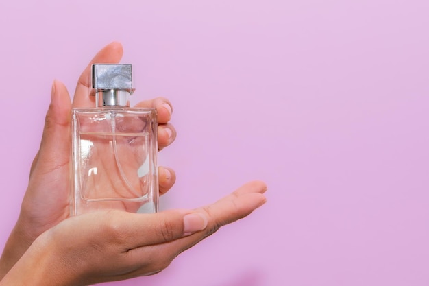 Mão de mulher segurando uma garrafa de perfume
