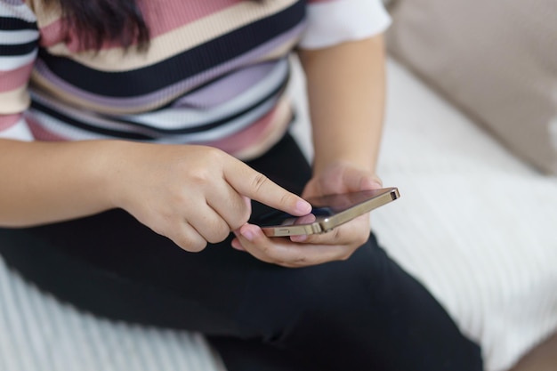 Mão de mulher usando smartphone para verificar mídias sociais ou mulher lendo e-book na tela