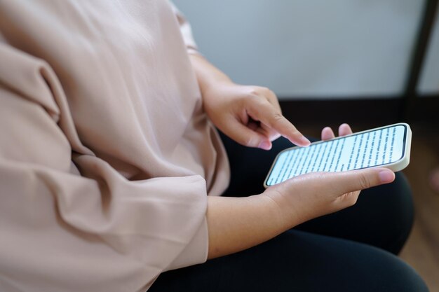 Mão de mulher usando smartphone para verificar mídias sociais ou mulher lendo ebook na tela