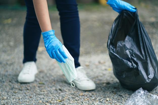 Mão de mulher voluntária de caridade segurando máscara protetora cirúrgica durante a pandemia de coronavírus Covid19 jogando fora máscara facial protetora usada no conceito de máscara descartada de lixo