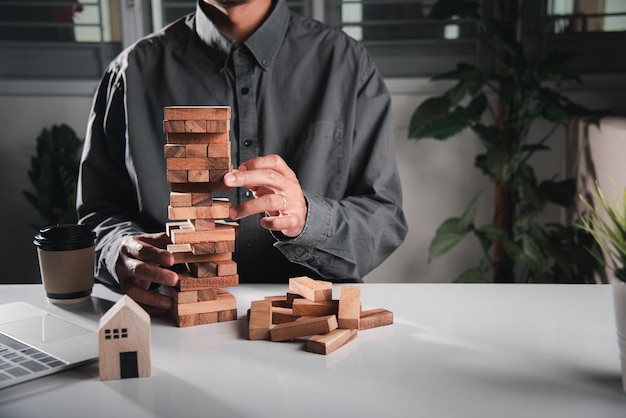 Mão de negócios jogando jogo de blocos de madeira de torre