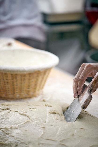 Mão de padeiro moldando pães para assar