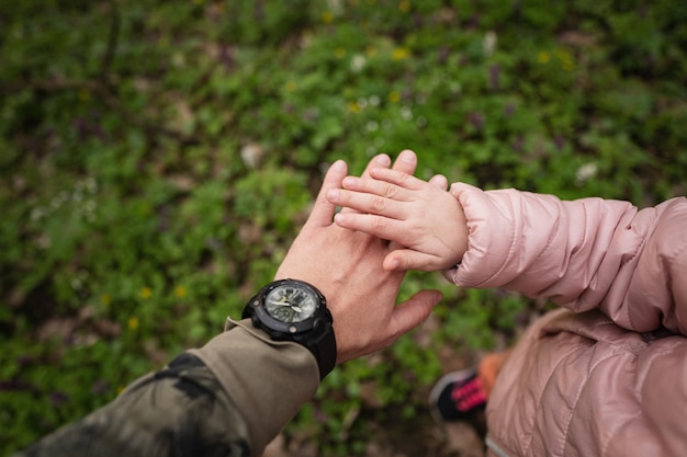 Mão de pai e filha na floresta de primavera