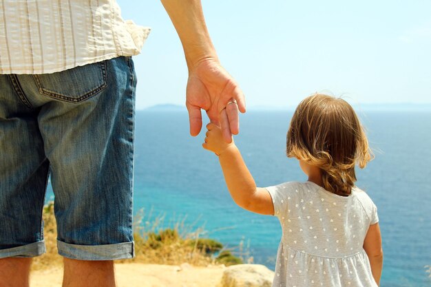 Mão de pai e filho perto do mar