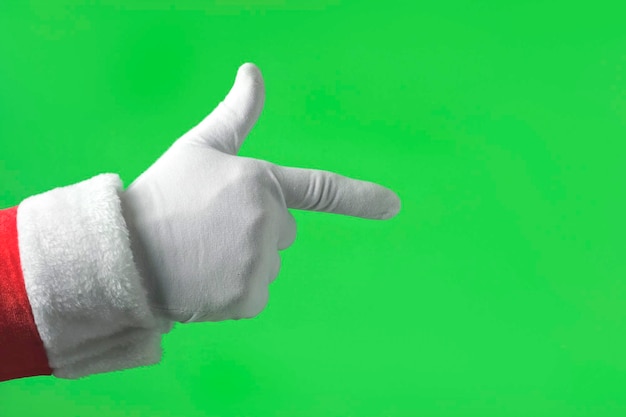 Mão de Papai Noel apontando para a frente com o dedo indicador isolado em fundo verde Feche a mão enluvada branca aponta para a frente em algo com um dedo Chroma Key Screen Gesto de propaganda