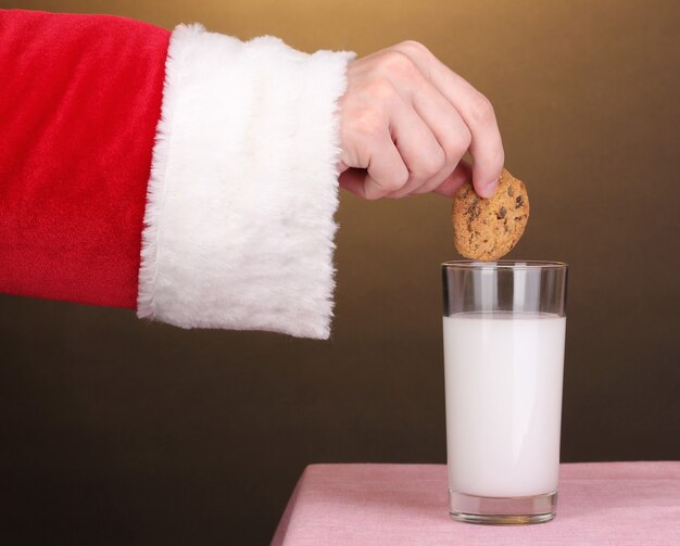 Mão de Papai Noel segurando biscoito de chocolate