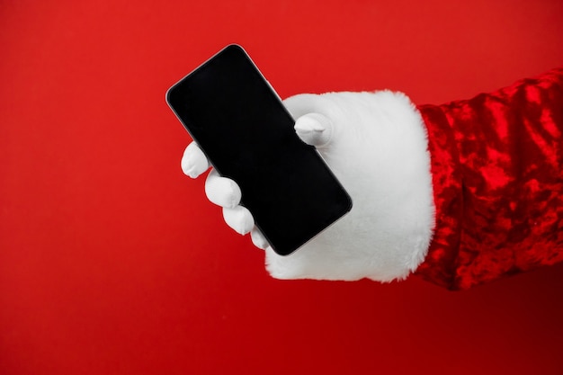 Mão de papai noel segurando um smartphone com uma tela em branco.