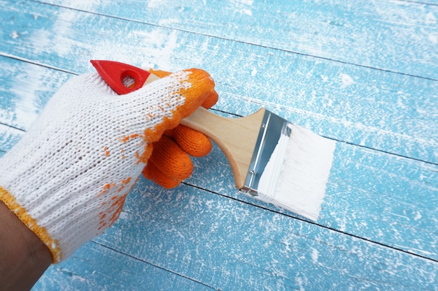 Foto mão de pintor segurando pincel pintar a madeira azul