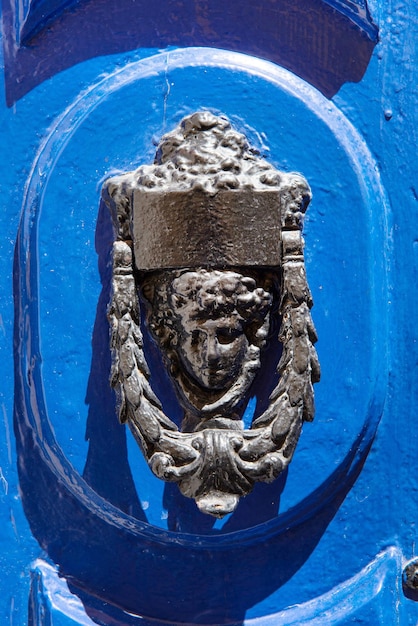 Mão de porta de bronze decorativa na forma de uma bela cabeça de mulher em uma porta pintada de azul Malta