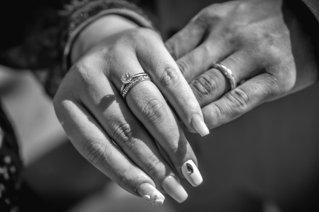 Mão de recém-casados com os anéis recém-colocados após o casamento, fotografia em preto e branco