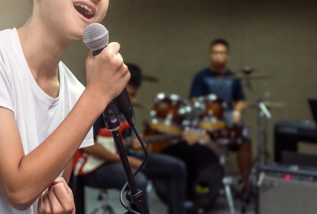 Foto mão de songer segurando o microfone e cantando no músico