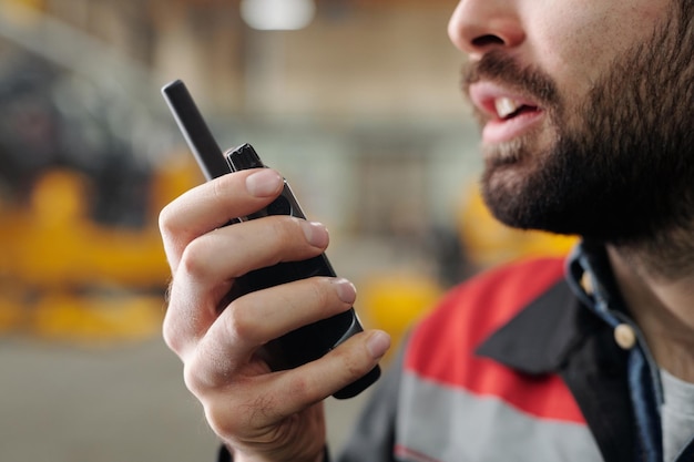Mão de trabalhador barbudo de planta falando em transceptor de rádio portátil