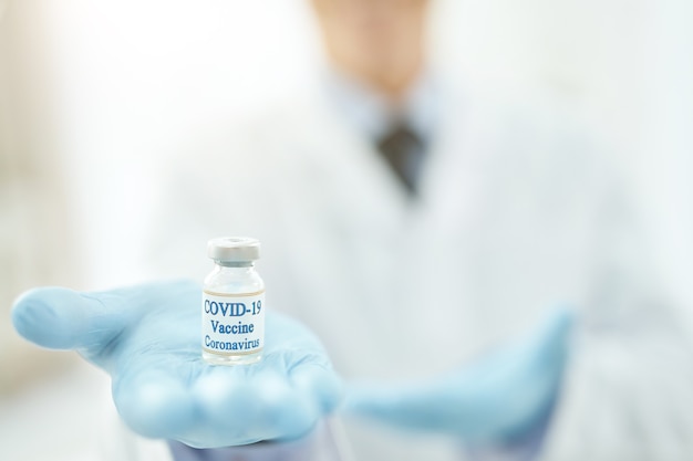Mão de trabalhador médico segurando frasco de vacina contra coronavírus