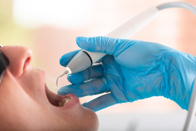 Mão de um dentista em uma luva com uma ferramenta em close-up de mãos. Odontologia moderna, close-up, cópia espaço.