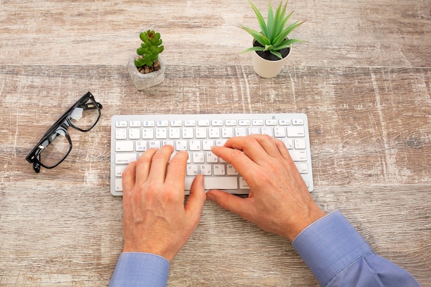 Mão de um homem digitando no teclado branco